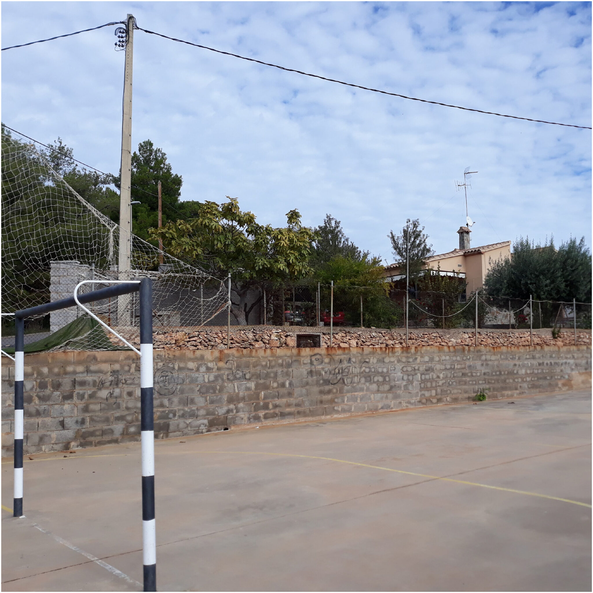Outdoor soccer goal near stone wall and house