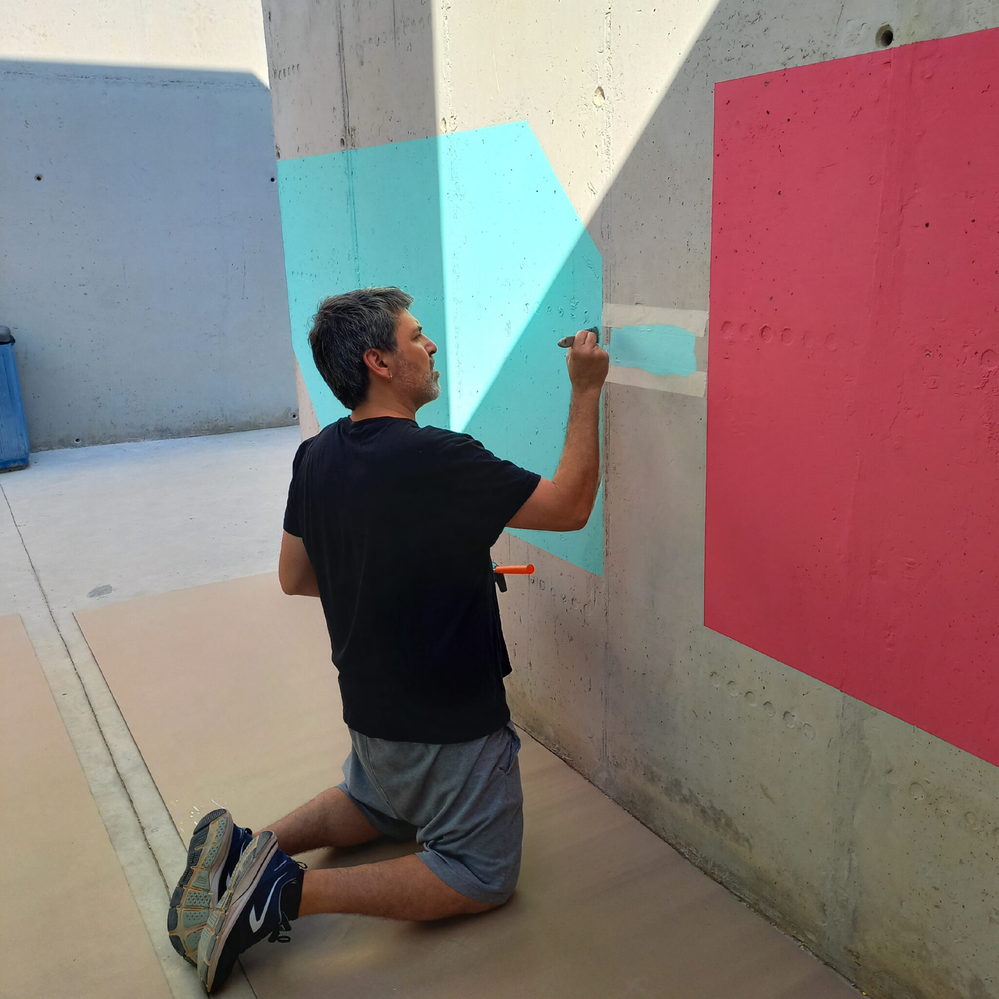 Man painting colorful geometric shapes on concrete wall